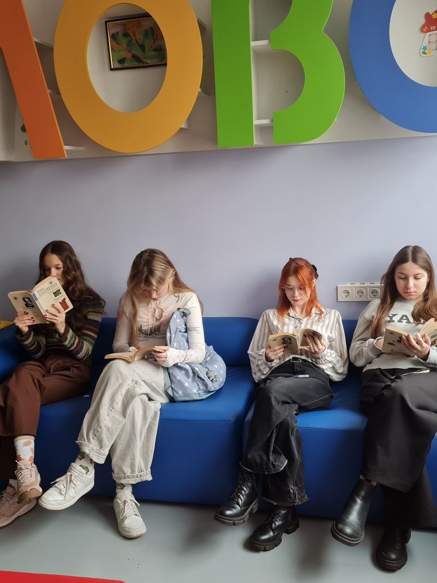 Des adolescentes lisent sur un canapé, dans une bibliothèque