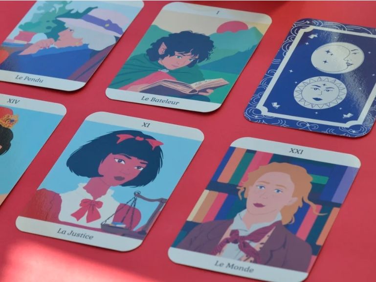 Des cartes du Tarot littéraire étalées sur une table rouge